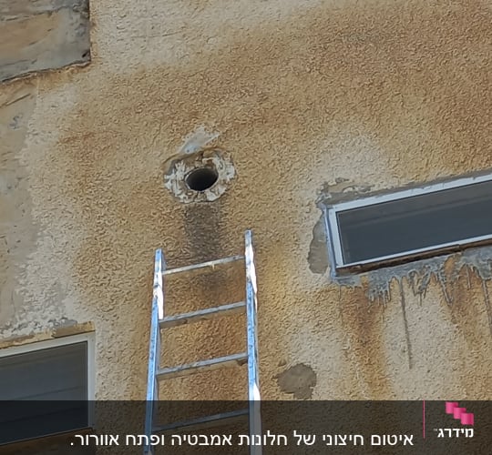 סולם ליד חור בקיר חיצוני של בניין